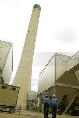 Workers at power station walking with smokestack in background - Mining Photo Stock Library