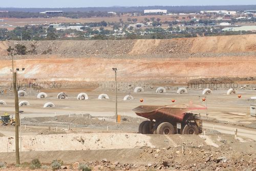 Haul truck parked up at go line in open cut mine.  township of kalgoorlie in background - Mining Photo Stock Library
