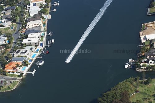 Aerial shot of jetski or small water craft on canal with residential houses all around. - Mining Photo Stock Library