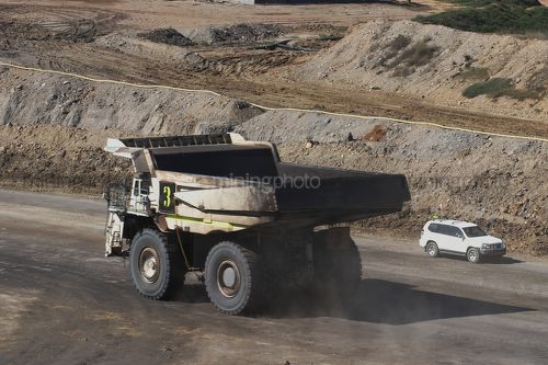 Haul truck and light vehicle pass on haul road in open cut mine site. - Mining Photo Stock Library