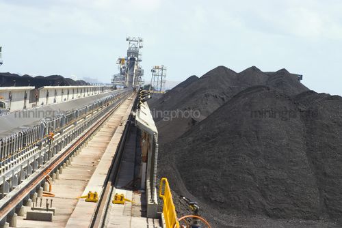 Coal spreader and reclaimer at terminal.  shot looking along tracks with coal stockpiles adjacent. - Mining Photo Stock Library