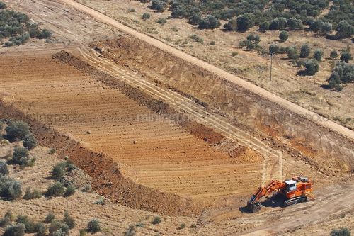 Excavator stripping topsoil prior to mining.  unsual photo taken as an aerial. - Mining Photo Stock Library