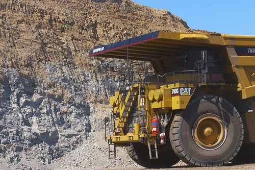 Close up photo of yellow haul truck in open cut coal mine with coal high walls behind. - Mining Photo Stock Library