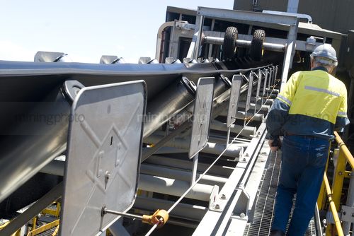 Mine worker on walkway adjacent to a conveyor. - Mining Photo Stock Library