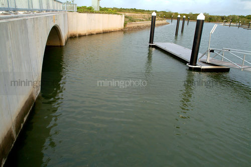 Road bridge into clean waterfront property subdivision. jettys and pontoons in water. - Mining Photo Stock Library