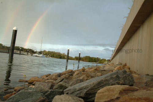 Rainbow over water in waterfront property subdivision - Mining Photo Stock Library