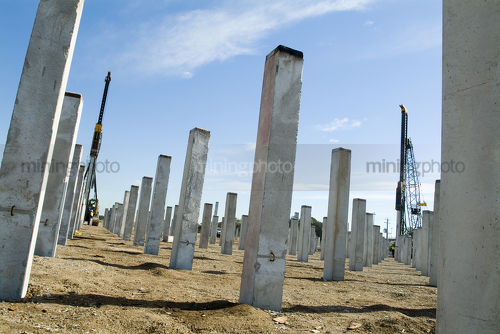 Piledriver hammers pre cast concrete piers into the ground as foundation - Mining Photo Stock Library