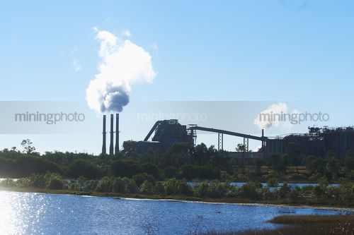 Water storage dam in foreground with generic refinery and industry in background. - Mining Photo Stock Library