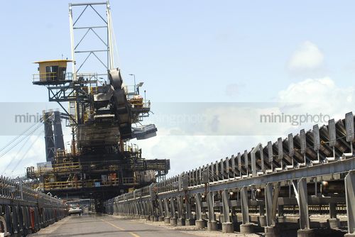 Long shot of a ship loader at a coal terminal.  photo taken at ground level.  parked light vehicle gives scale. - Mining Photo Stock Library