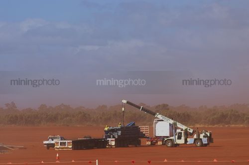 Mine workers in full PPE using a crane to unload a B Double truck at remote mine site. - Mining Photo Stock Library