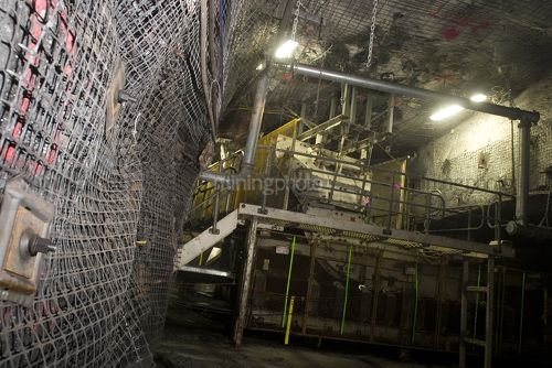 Close up photo of underground wall mesh in under ground coal mine.  machinery in the background. - Mining Photo Stock Library