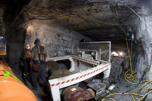 Workers in full PPE working together in underground coal mine.  mine machinery truck nearby. - Mining Photo Stock Library