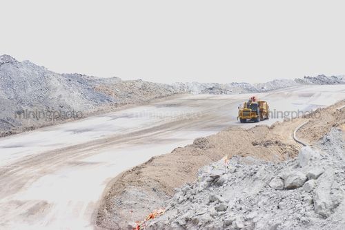 Earth scraper driving down haul access road in open cut mine site. - Mining Photo Stock Library