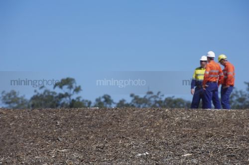 Three mine site workers in full PPE in discussion.  workers out of focus.   - Mining Photo Stock Library