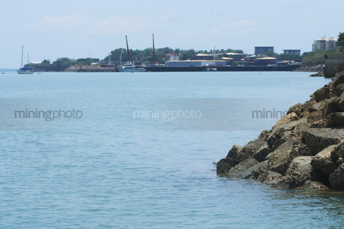 Photo looking over bay rock wall with town and wharves in the background. - Mining Photo Stock Library