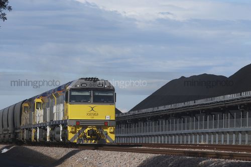 Coal train next to coal stockpiles. - Mining Photo Stock Library