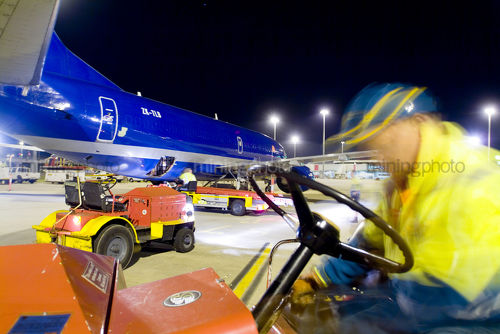 Workers in PPE involved in loading a large cargo plane with freight at night at airport. - Mining Photo Stock Library