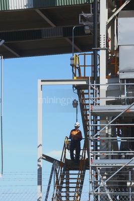 Mine worker in full PPE walking down stairs from conveyor site. - Mining Photo Stock Library