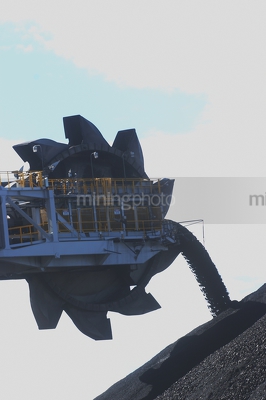 Close up silhouette of a coal loader stockpiling coal. - Mining Photo Stock Library