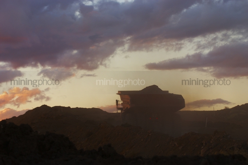 Silhouette of loaded haul truck on mine site.  photo taken at dusk. - Mining Photo Stock Library