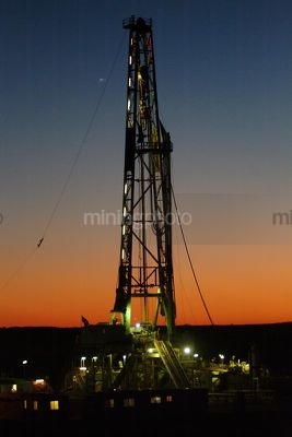 Drill rig derrick with lights on shot at sunset. - Mining Photo Stock Library