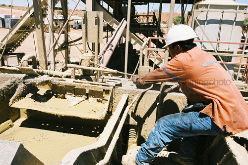 Oil and gas rig worker tightening a valve on a rig.  shot from the side. - Mining Photo Stock Library