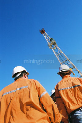 Drill rig workers with derrick behind - Mining Photo Stock Library