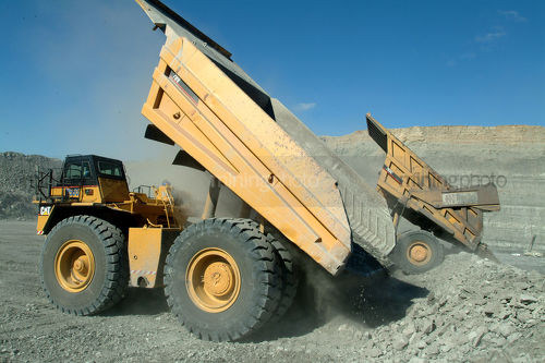 Haul trucks emptying coal overburden onto stockpile - Mining Photo Stock Library