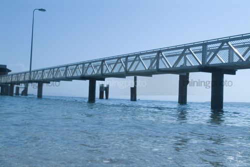 Pedestrian jetty out to passenger ferry terminal over ocean.  shot from water level. - Mining Photo Stock Library
