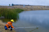 Mining Photo Stock Library - mine environment worker taking water samples from dam at open  cut mine.  haul truck on road in background. ( Weight: 1  New Image: NO)