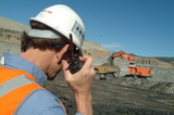 Mining Photo Stock Library - mine site supervisor listening to radio with excavator loading haul truck in background. ( Weight: 3  New Image: NO)