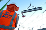 Mining Photo Stock Library - site worker watching large concrete girder being craned into position with overhead rail electricity wires. ( Weight: 3  New Image: NO)