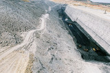 Mining Photo Stock Library - three truck rotation with digger on coal seam floor with steep high walls.  water cart in background and long haul road behind. midden overburden stockpiles on side.  image shows scale of huge size and depth of mine.   ( Weight: 1  New Image: NO)