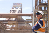Mining Photo Stock Library - process engineer onsite in full ppe wearing ear plugs gazing upwards with arms folded.  pipeline and plant in background.  worker is on right hand side of frame.  great generic shot. ( Weight: 1  New Image: NO)