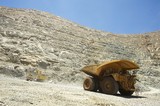 Mining Photo Stock Library - wide shot at ground level of loaded haul truck leaving the deep open cut pit floor.  excavator and dozer in background at base of high wall.  blue sky and high walls above.  gold mine. ( Weight: 1  New Image: NO)
