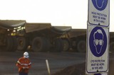 Mining Photo Stock Library - hearing and head protection safety signs in focus with mine haul truck driver in full PPE walking from truck go line in background. ( Weight: 1  New Image: NO)