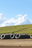 Mining Photo Stock Library - truck tyre stock pile on mine site with green revegetation in the background.  vertical image. ( Weight: 1  New Image: NO)