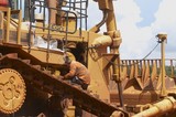 Mining Photo Stock Library - mine worker servicing a large dozer at a workshop at a mining site. ( Weight: 1  New Image: NO)