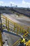 Mining Photo Stock Library - mine site worker in full PPE walking down stairs with 3 three points of contact.  coal terminal with reclaimers in the background.  vertical photo. ( Weight: 1  New Image: NO)