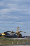 Mining Photo Stock Library - photo of large shiploader and reclaimer working on coal stockpiles. light vehicle sealed road in foreground.  vertical photo. ( Weight: 1  New Image: NO)