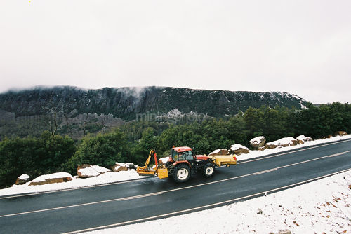 Snow plow tractor clearing road in mountain high pass. - Mining Photo Stock Library