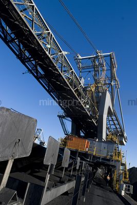 Worker in ppe walking under coal reclaimer at terminal - Mining Photo Stock Library