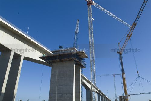 Bridge construction with many cranes and pre cast concrete pylons. - Mining Photo Stock Library