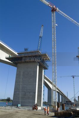 Highway bridge construction with 2 workers in foreground  - Mining Photo Stock Library