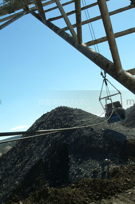 Dragline bucket swinging through air above overburden stockpile vertical image - Mining Photo Stock Library