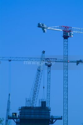 Multi level cranes lifting concrete and steel into position on large construction job. generic image. vertical shot - Mining Photo Stock Library
