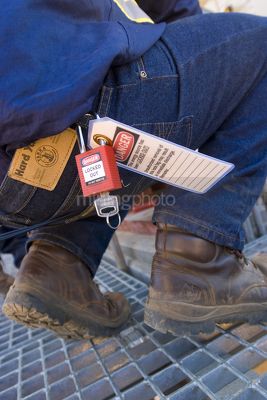 Close up of mine worker from the waist down showing safety lock out tags and padlock on belt. - Mining Photo Stock Library