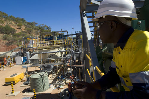African mine worker looking out towards the processing plant site. - Mining Photo Stock Library