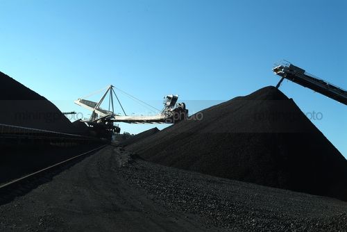 Coal reclaimer and track conveyor loader working on coal stockpiles - Mining Photo Stock Library