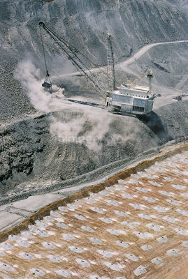 Dragline stockpiling overburden in open cut coal mine with filled blast holes in foreground awaiting blasting. vertical shot - Mining Photo Stock Library